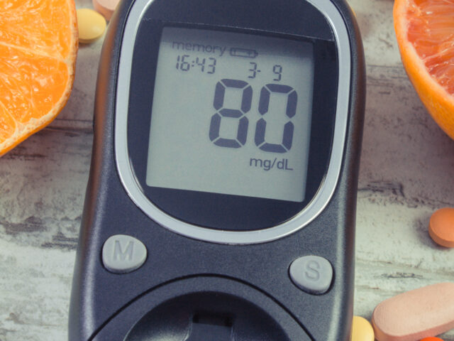 Glucometer with result of sugar level, fresh fruits and medical pills. Diabetes and healthy lifestyle and nutrition